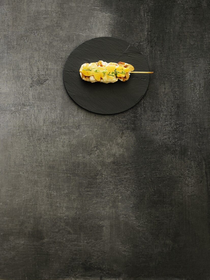 A kushi skewer on a round slate dish