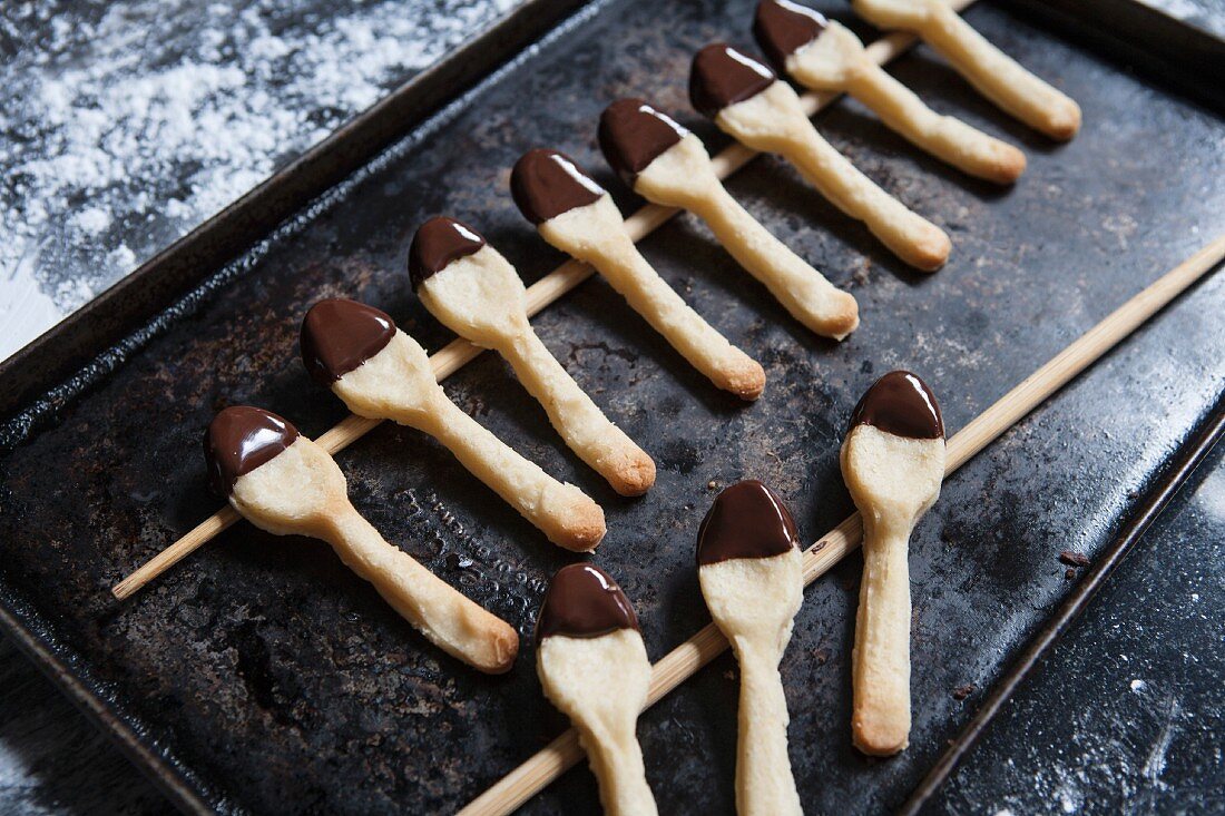 Spoon shaped biscuits dipped in chocolate glaze on a baking tray