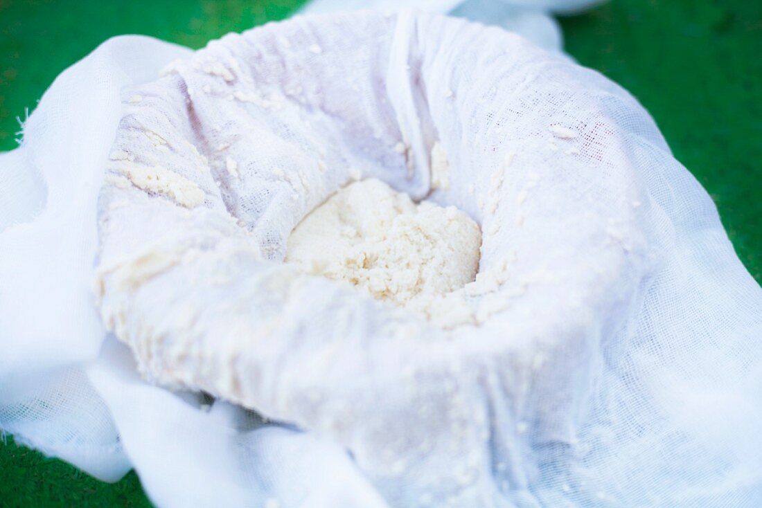 Homemade fresh ricotta in gauze on top of an earthenware dish