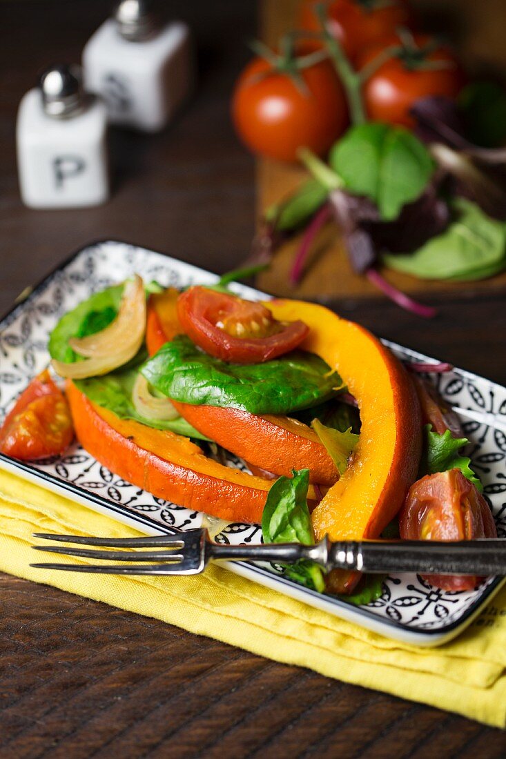 Ofengebratener Kürbis auf gemischtem Salat mit Tomaten und Zwiebeln