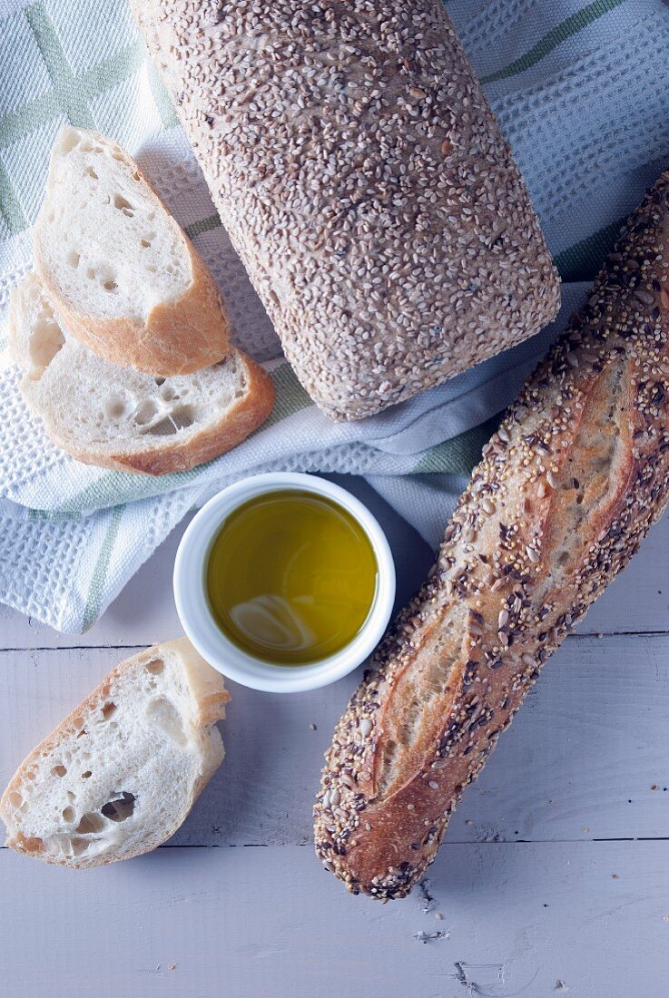 Seeded bread, baguette and olive oil (seen from above)