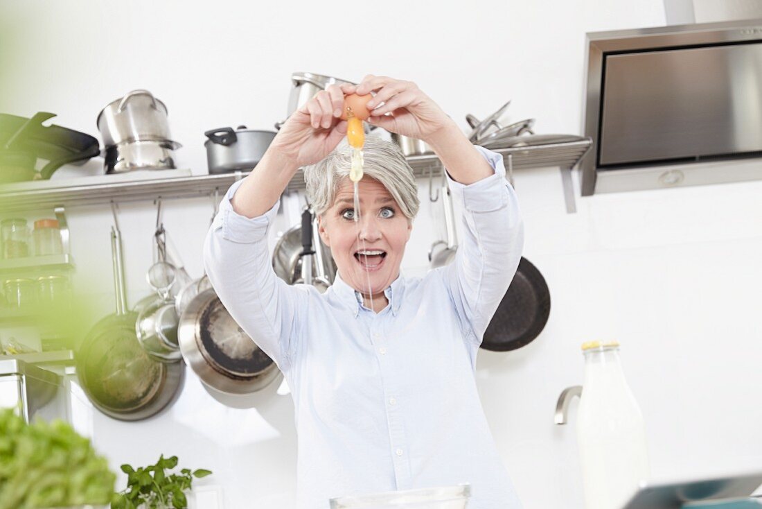 A middle-aged woman cracking eggs in a kitchen
