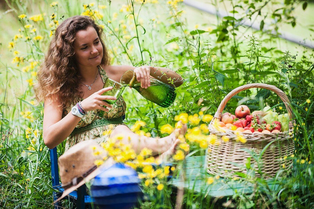 Junge Frau sitzt & relaxt in Bauerngarten (Altenmarkt-Zauchensee, Salzburger Land, Österreich)