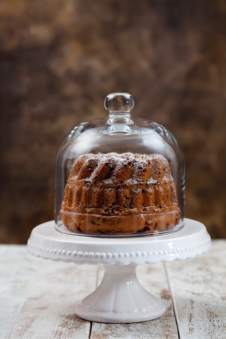 Kranzkuchen mit Schokoladenflocken unter Glas-Cloche