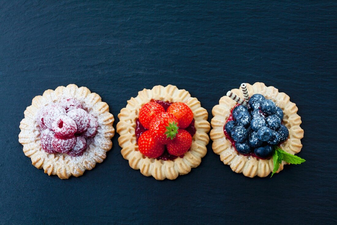 Three short crust fruit tartlets with raspberries, strawberries and blueberries
