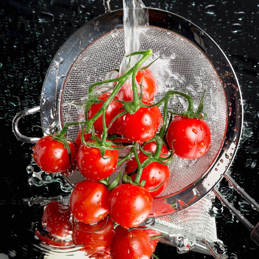 Tomaten werden in Küchensieb mit Wasser abgespült