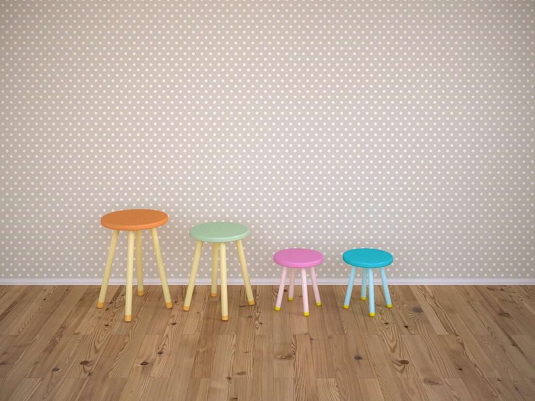 Four stools of different colours against wall with grey and white polka-dot wallpaper