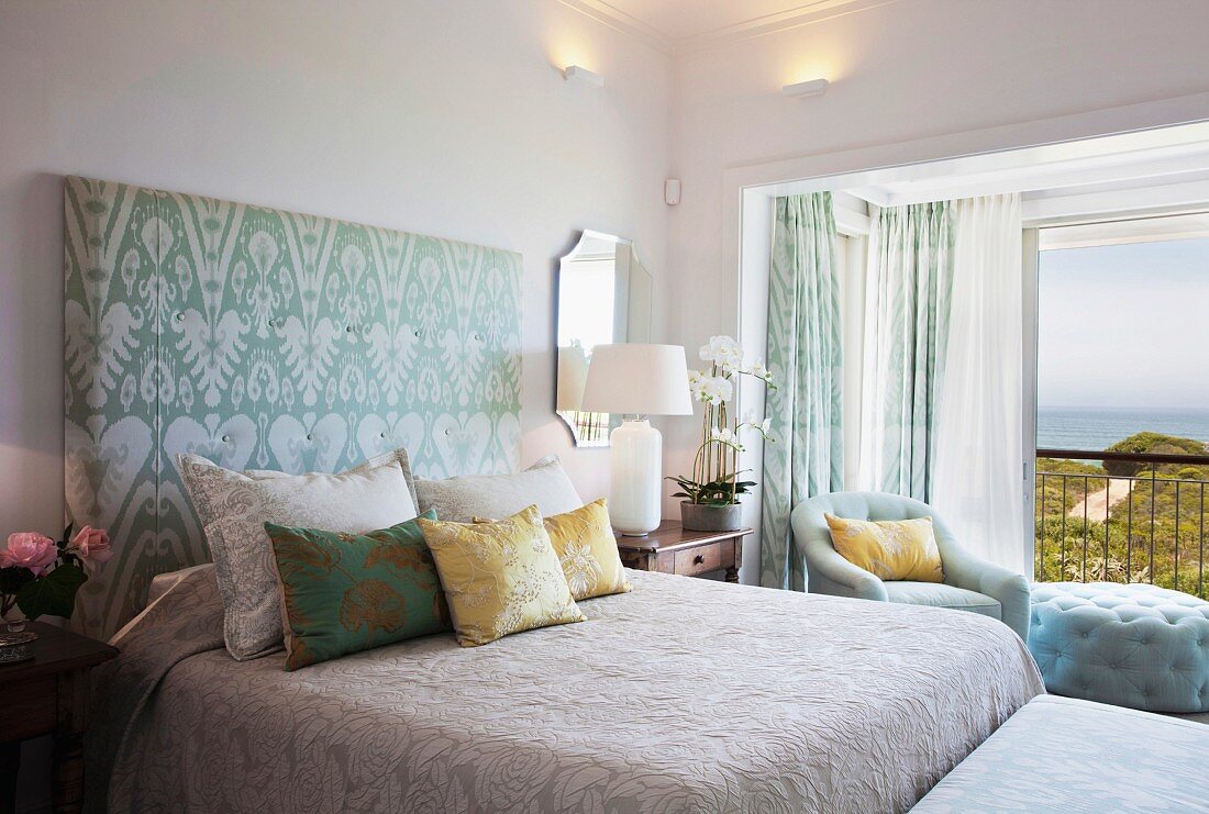 Bed with upholstered headboard in bedroom with sea view
