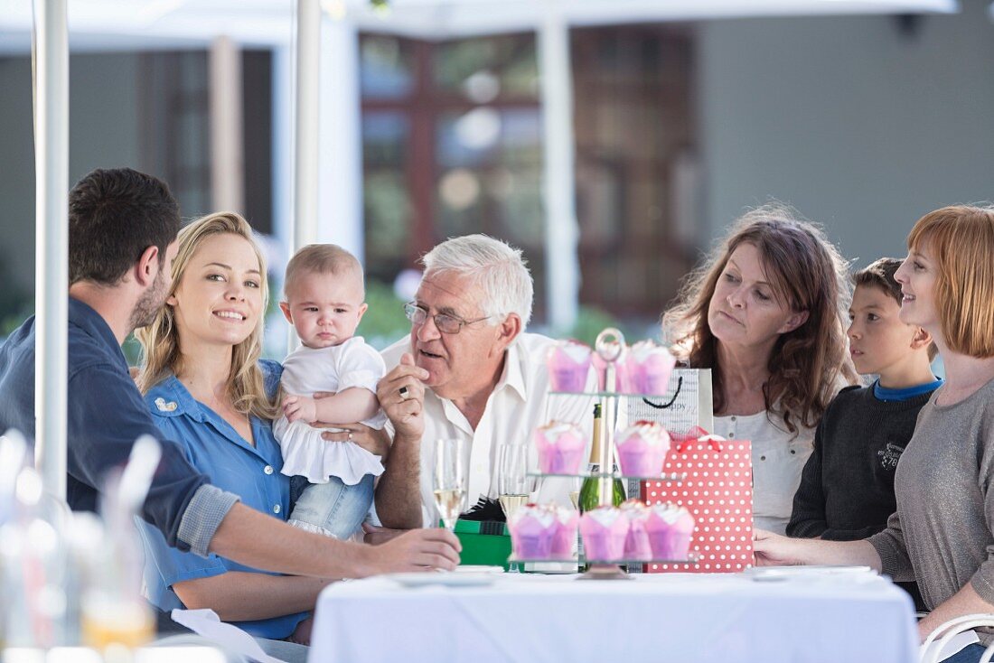Mehrgenerationenfamilie feiert Geburtstag an Tisch auf Restaurantterrasse