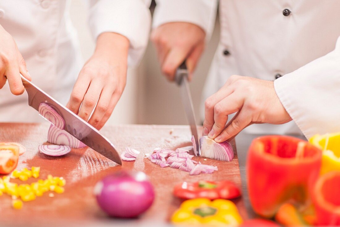 Chefs chopping onions in a restaurant kitchen