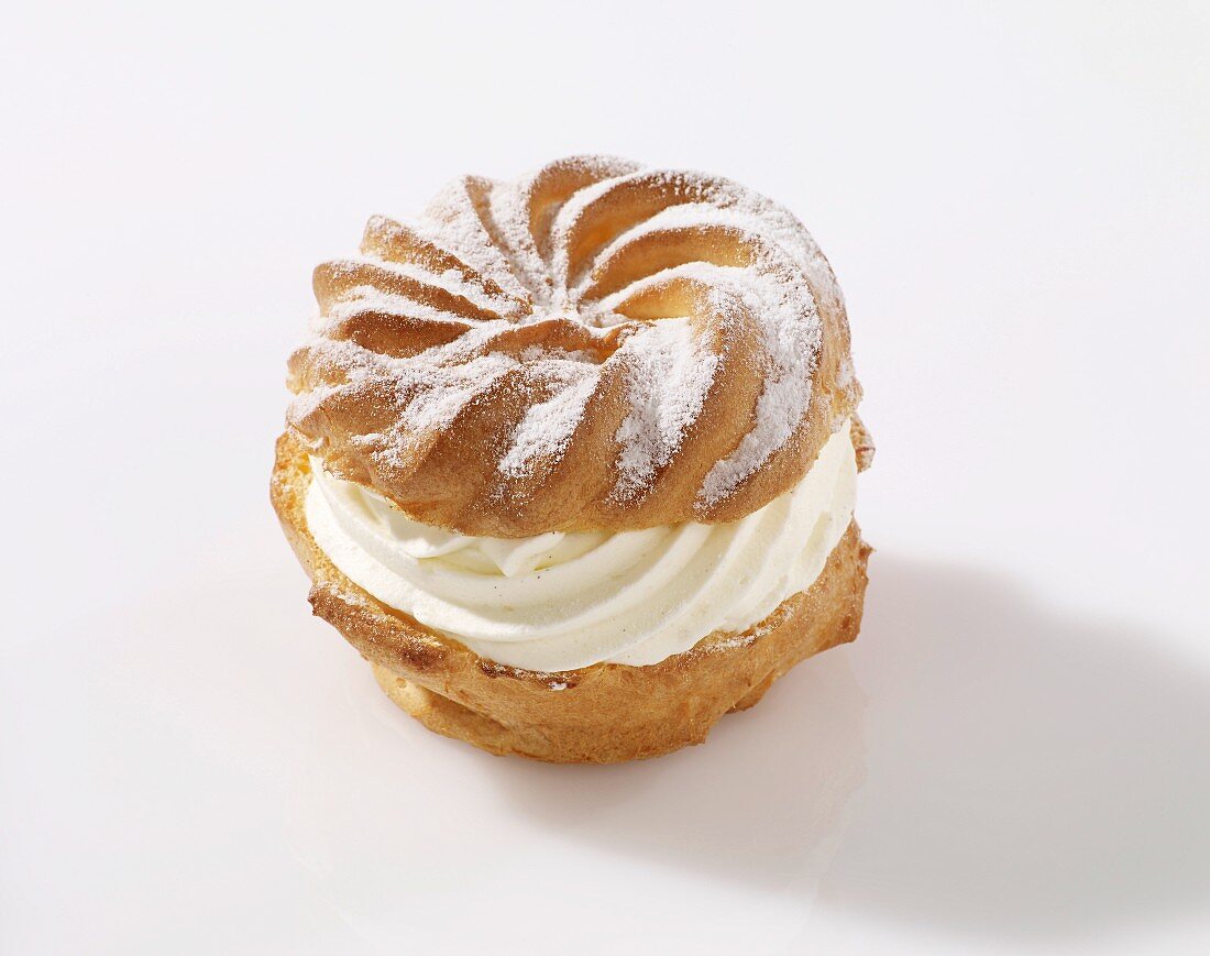 A profiterole with cream and icing sugar
