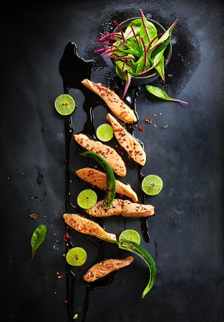 Fried salmon with black sesame seeds, chilli and limes (seen from above)