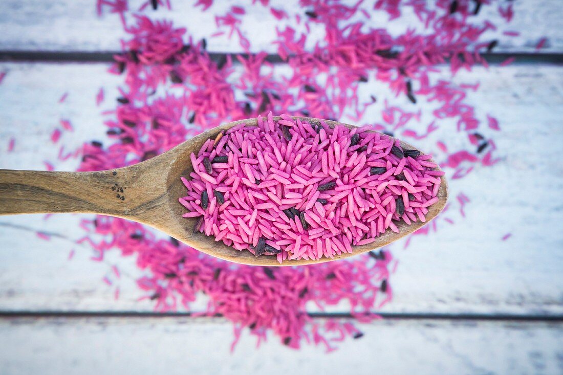 Pink, uncooked organic basmati rice on a wooden spoon (seen from above)