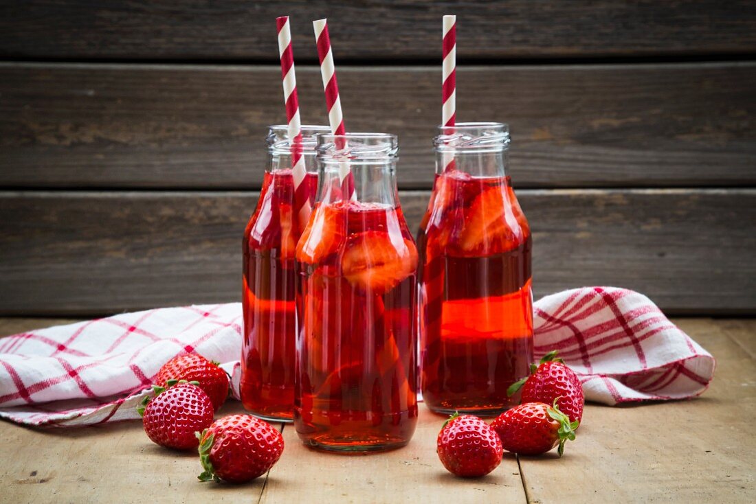 Selbstgemachte Erdbeerlimonate in Flaschen mit Strohhalmen