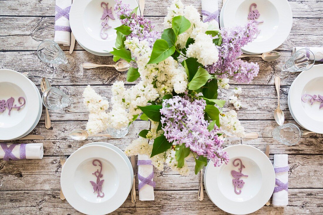 A festively laid spring table with a bunch of lilac (seen from above)