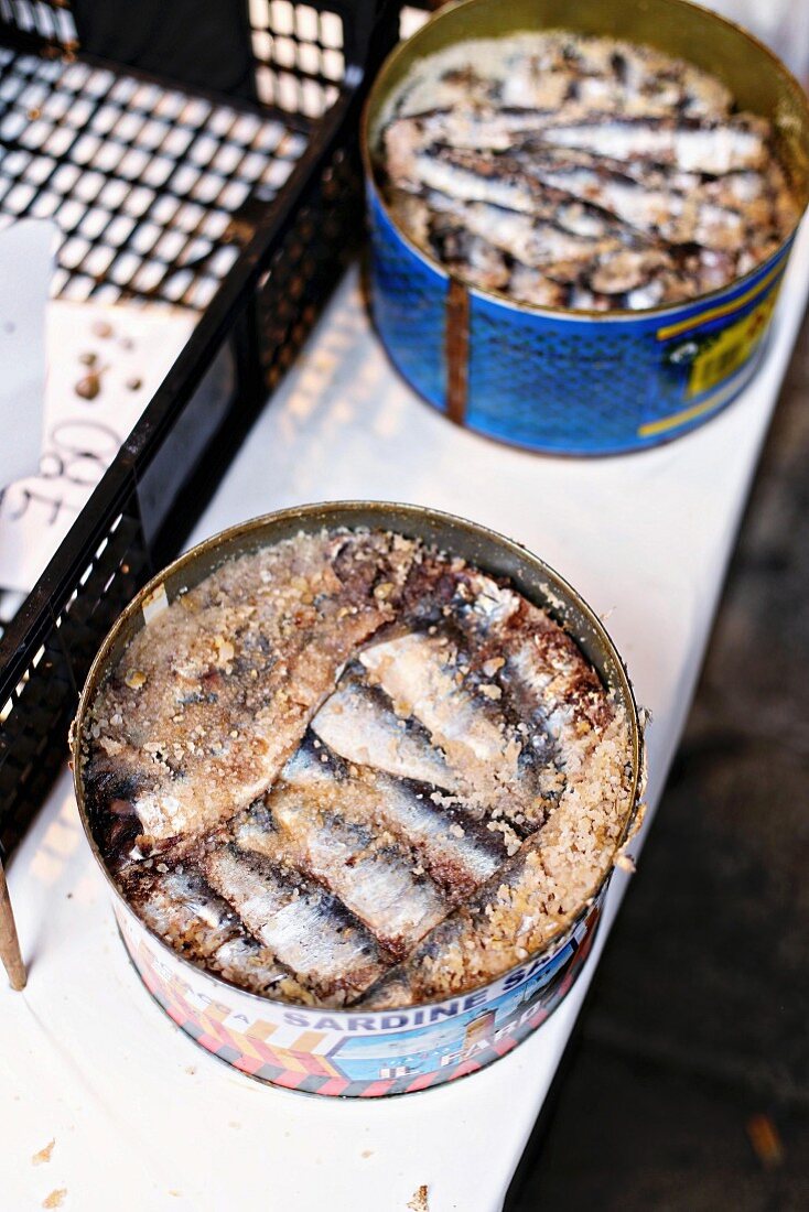 Salted sardines in metal tins at a fish market