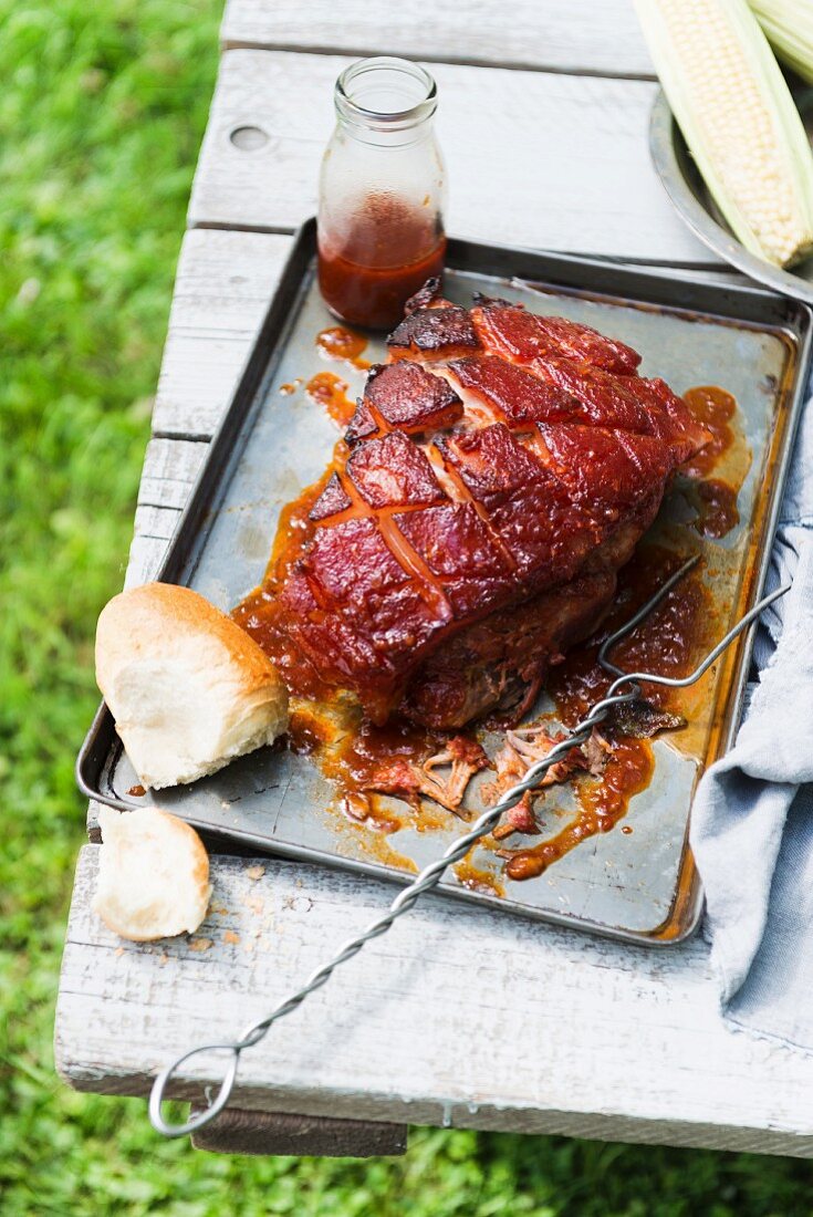 Grilled meat, a bread roll and barbecue sauce on a garden table