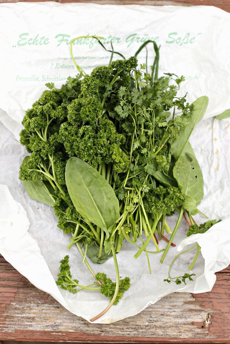 Herbs for Frankfurt green sauce on a piece of paper on a weathered wooden table