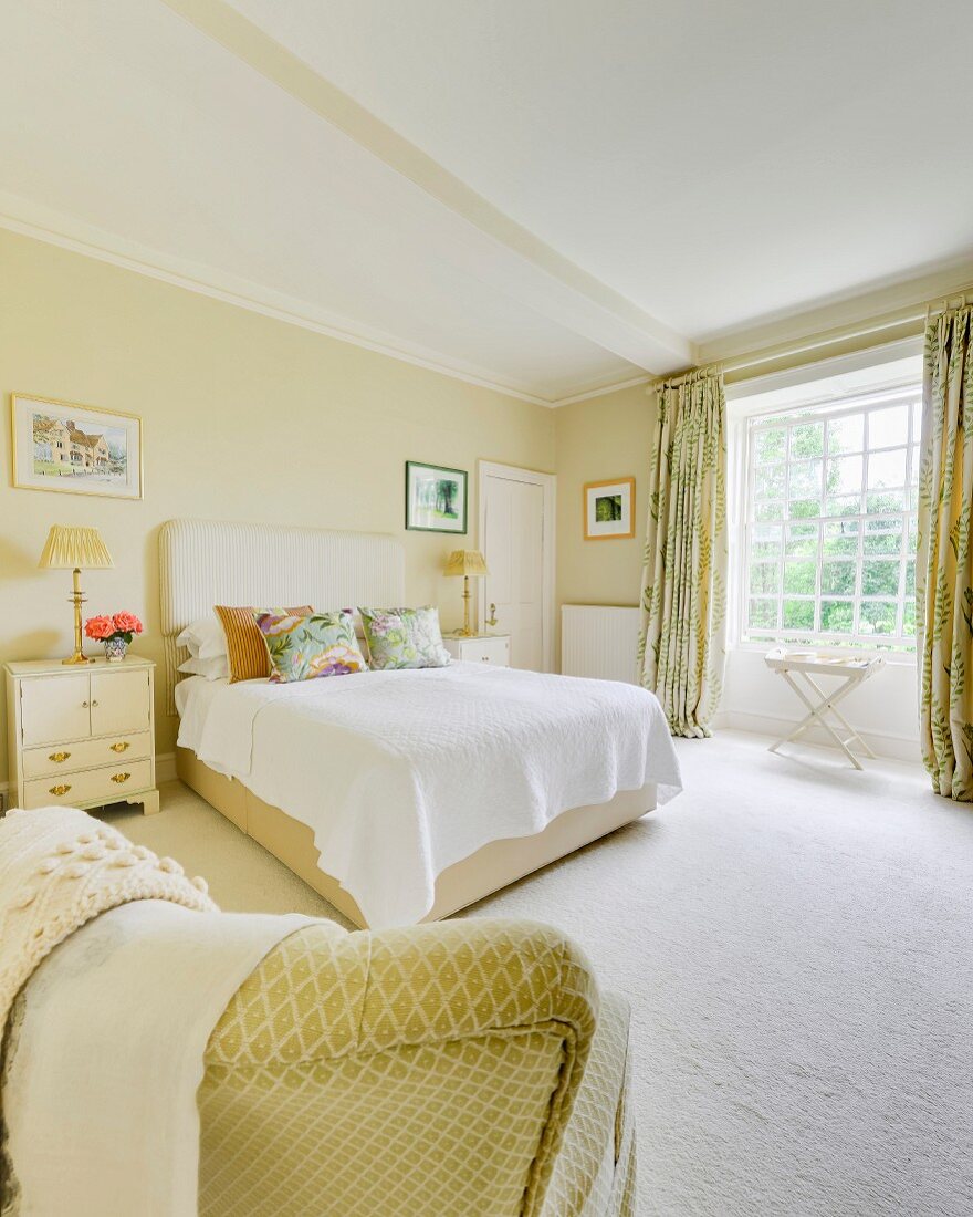 Double bed with upholstered headboard in bedroom painted pale yellow