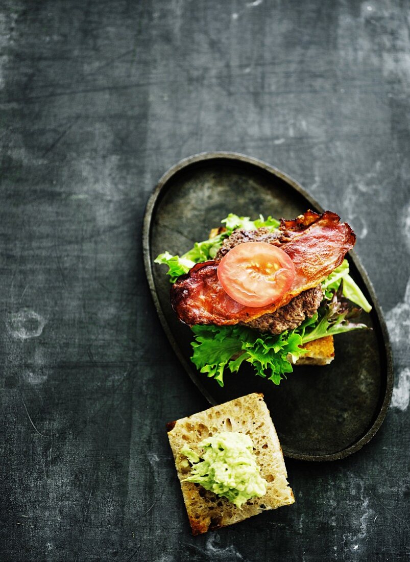 Burger auf Brot mit knusprigem Speck und Salatblatt