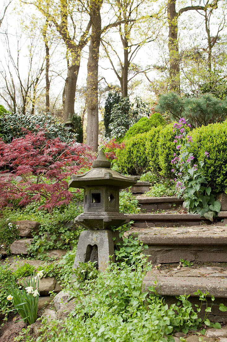 Kleine Pagode Laterne auf Steinpodest neben Treppestufen im Garten