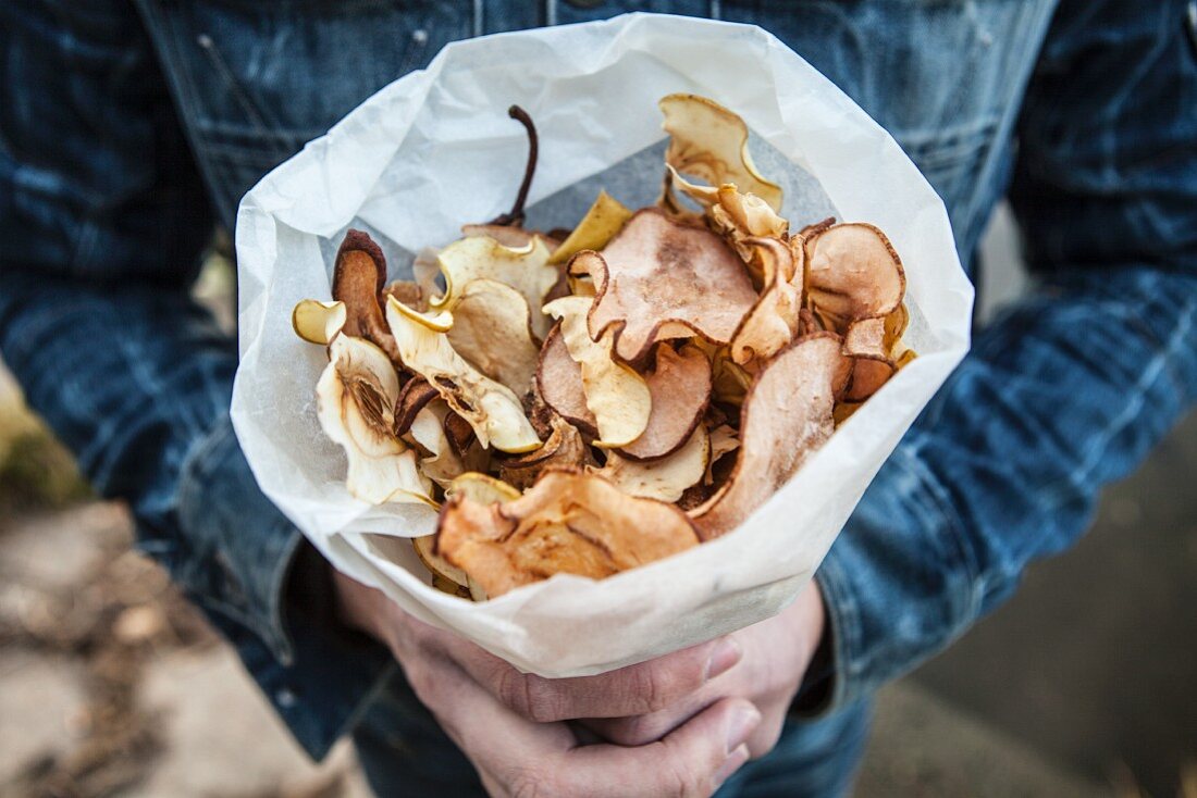 A person holding a paper bag of apple and pear crisps