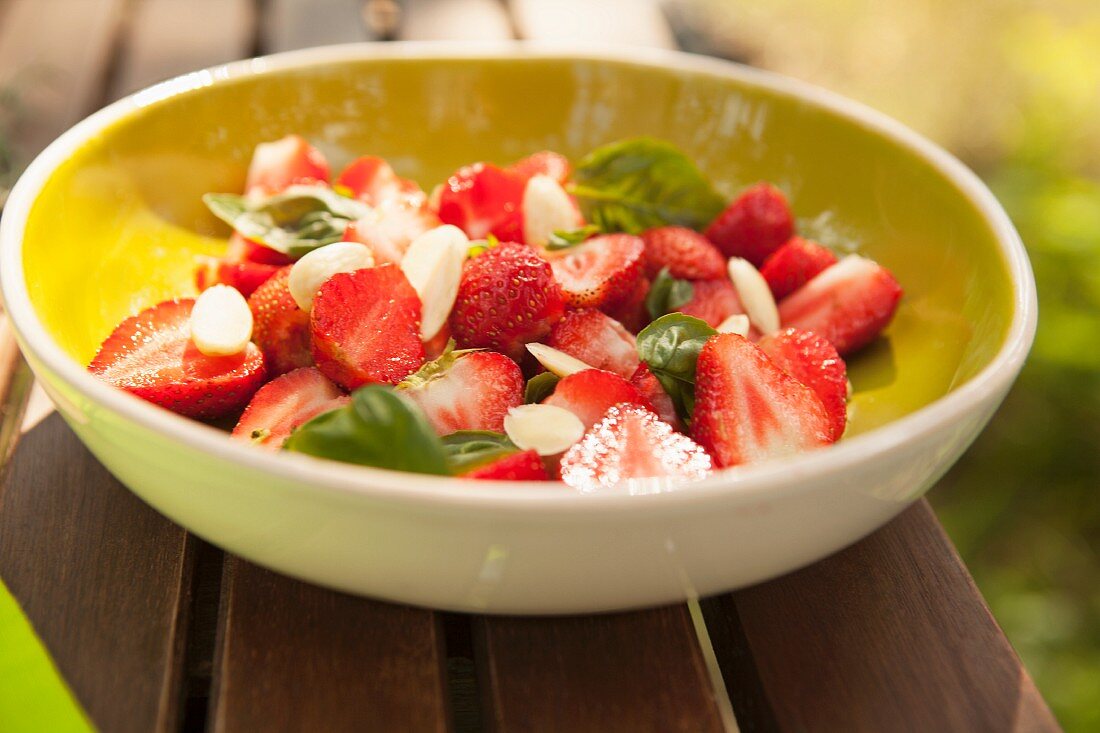 A strawberry salad with flaked almonds and basil