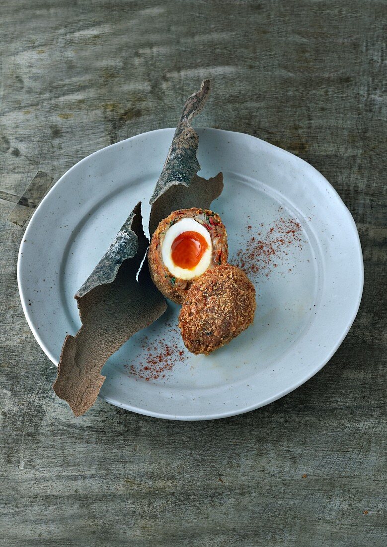 A Scotch egg, halved, on a plate