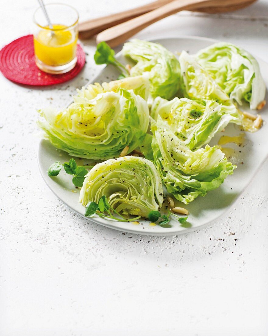 Sliced iceberg lettuce with an olive oil dressing and pine nuts