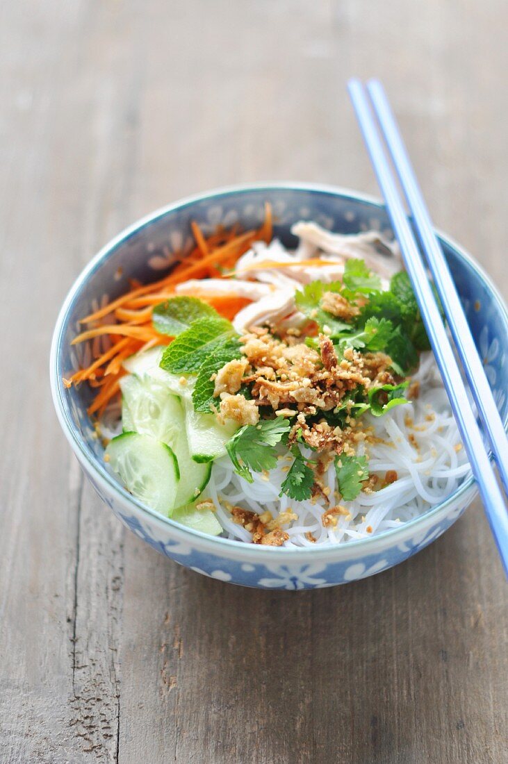 Rice noodles with chicken, vegetables, herbs and roasted onions