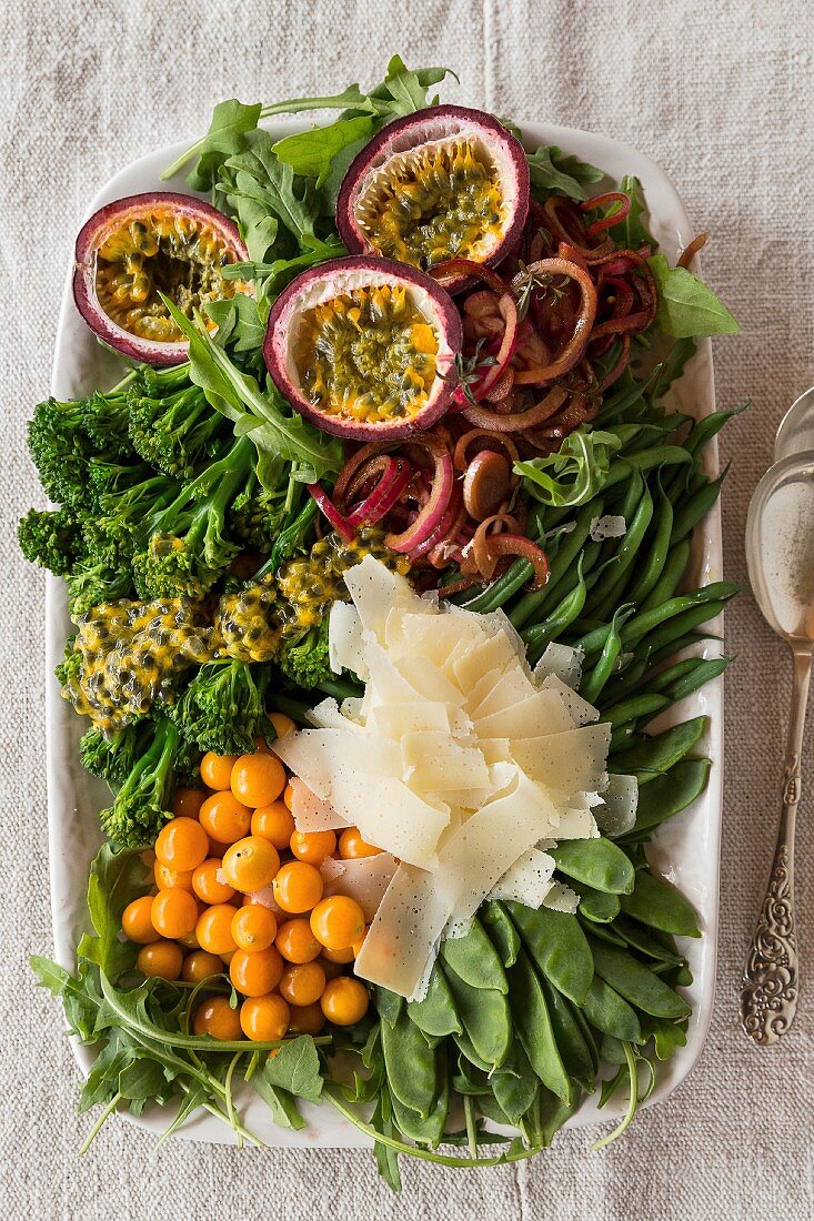 Grosser Salat mit grünem Gemüse, marinierter Zwiebel, Maracuja und Parmesan