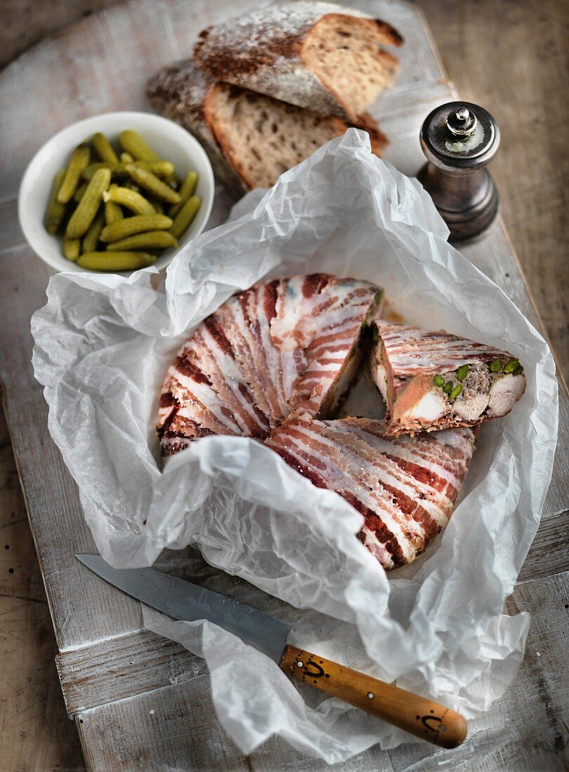 A rustic terrine wrapped in bacon with gherkins and bread