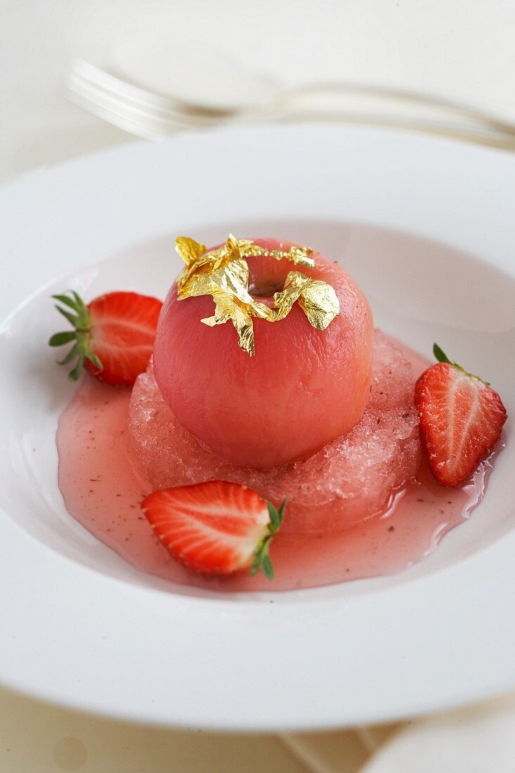 Poached peaches with gold leaf on strawberry granita