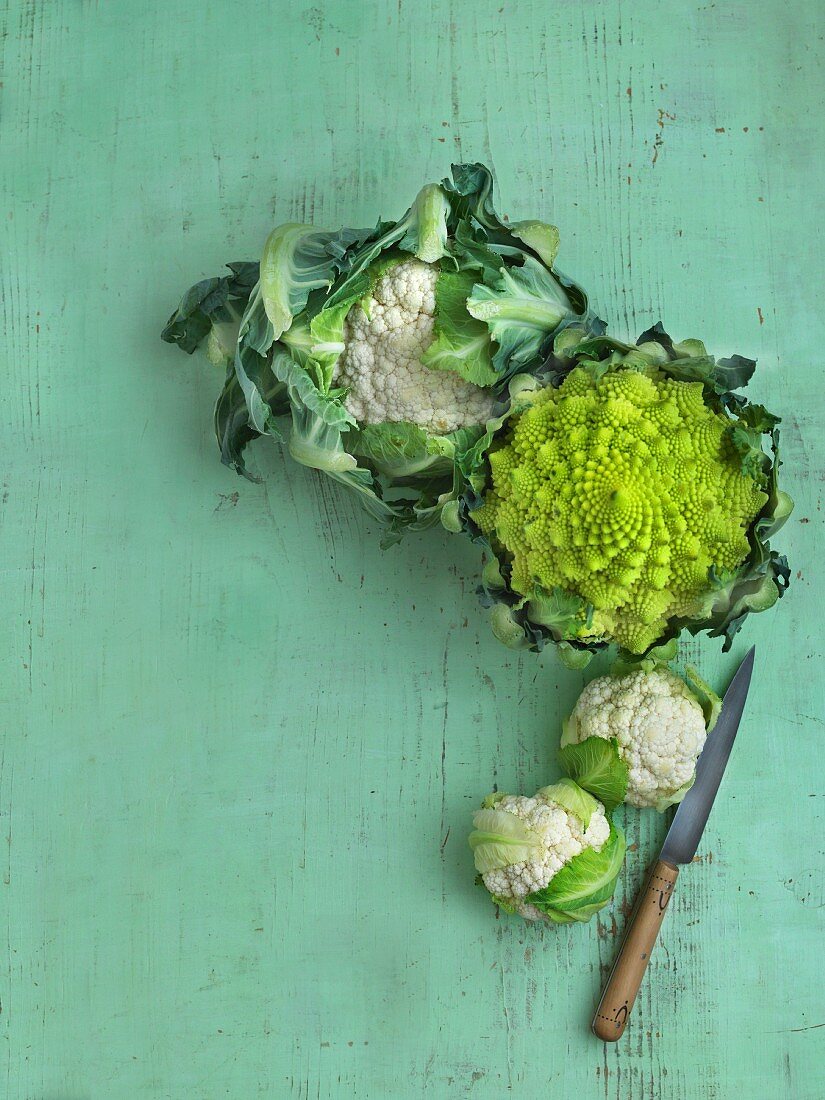 Cauliflower and Romanesco broccoli on a green wooden surface