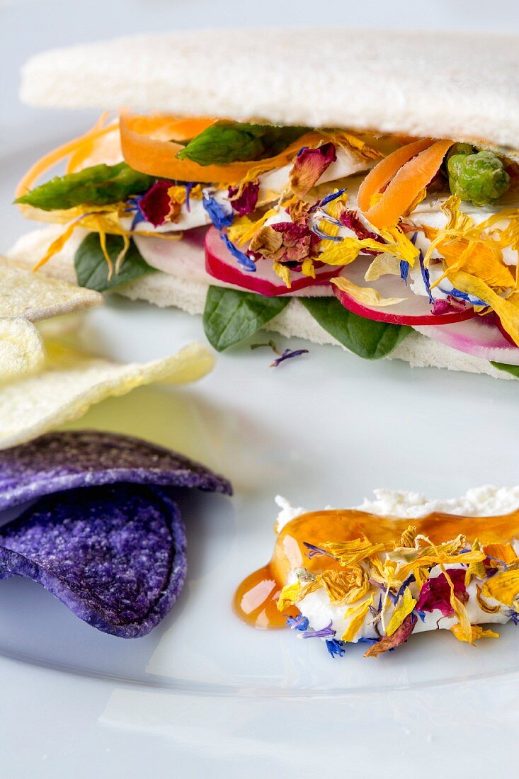 Goat's cheese, vegetable and edible flower sandwich served with colourful potato crisps