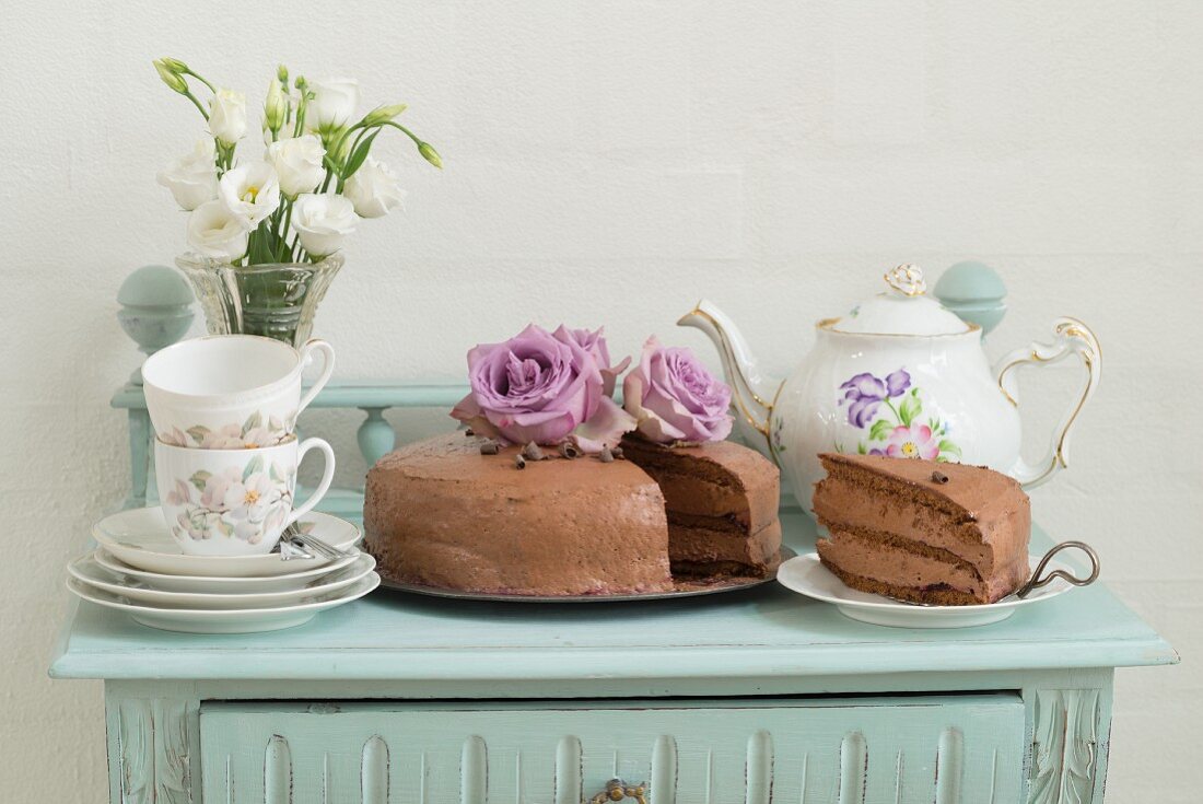 Chocolate cake with coffee crockery on a mint coloured sideboard