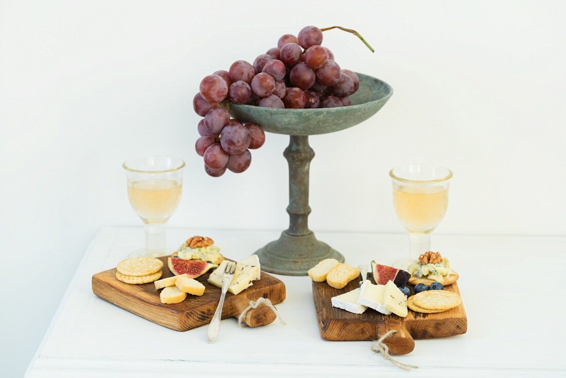 Small wooden boards with crackers, Brie, Danish caraway cheese, blue cheese, mini crostini, walnuts, fix, blueberries, grapes and Federweisser (a cloudy beverage in the process of fermenting, somewhere in between must and wine)