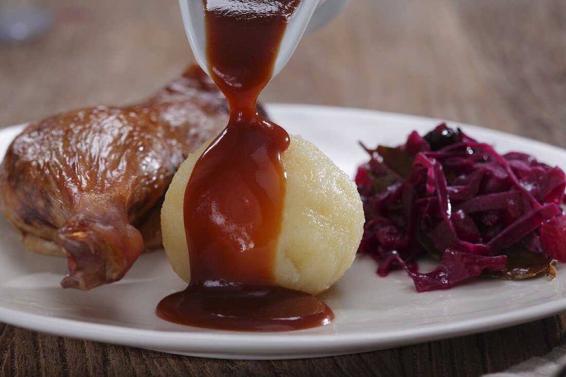 Gänsekeule mit Rotkraut & Knödel: Demi-Glace wird über Knödel gegossen