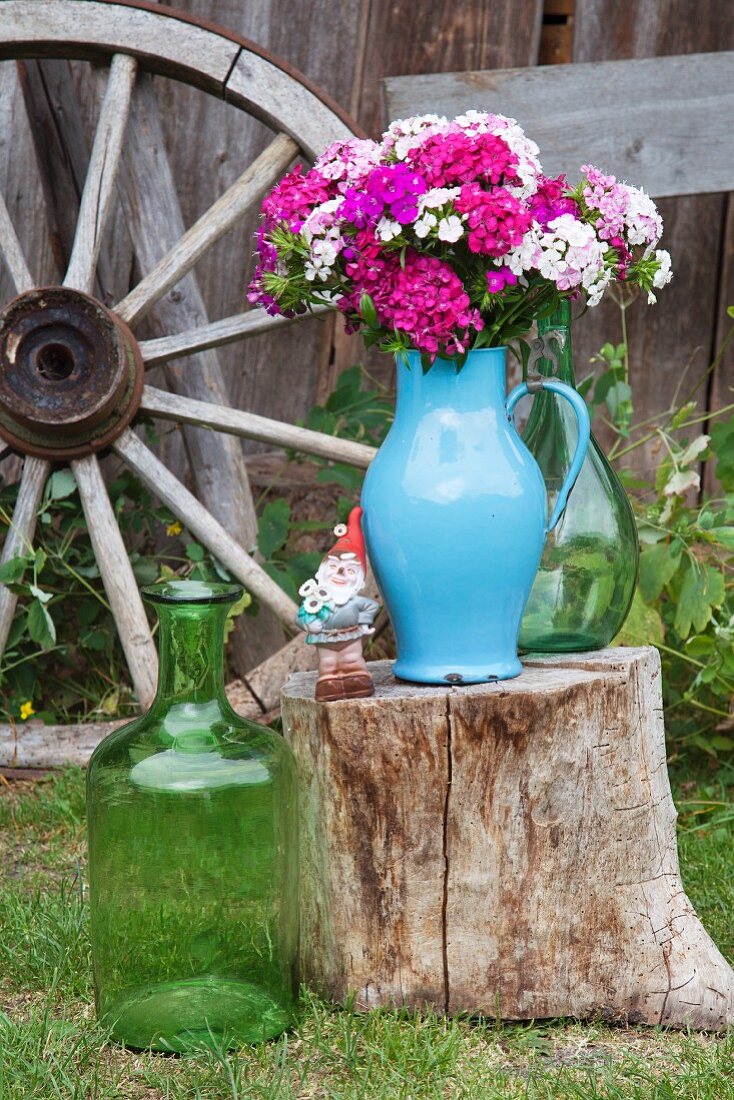 Blue enamel jug of Sweet William on tree stump