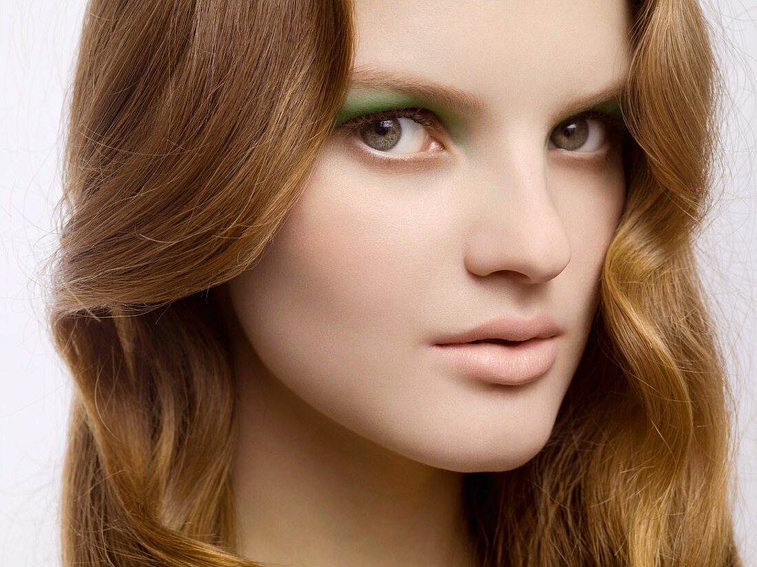 A close-up portrait of a young woman wearing green eyeshadow