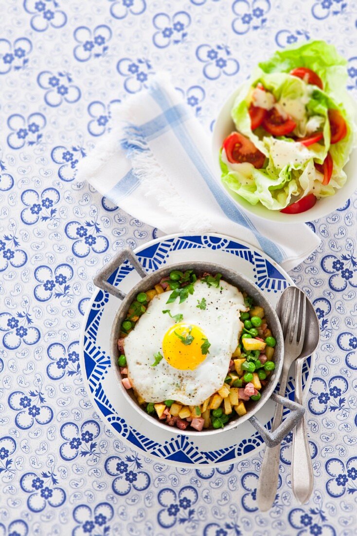 Fried potatoes with peas, bacon and fried egg