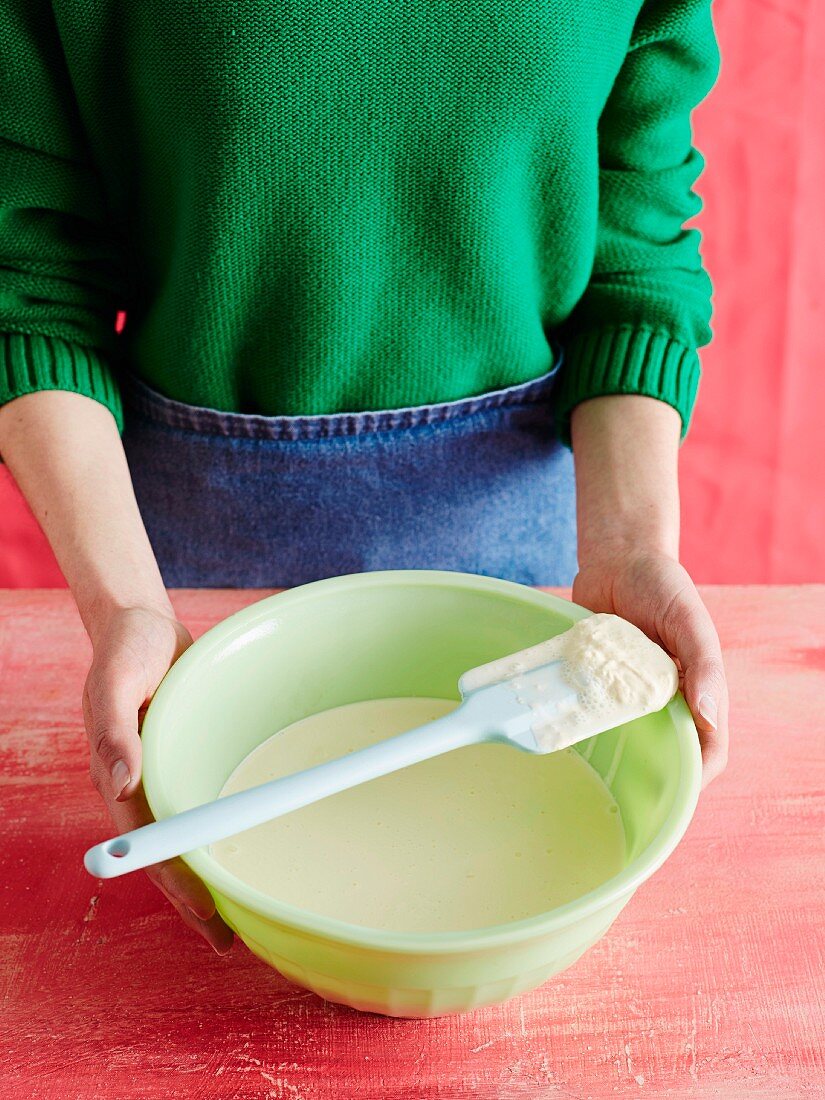 A woman holding a mixing bowl with a spatula