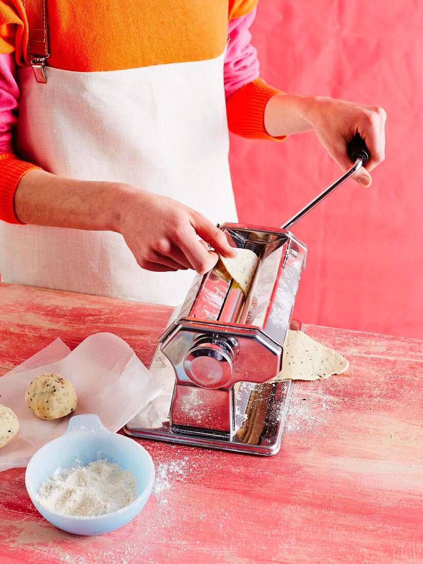 Crackers being made: a woman putting cracker dough through a pasta machine