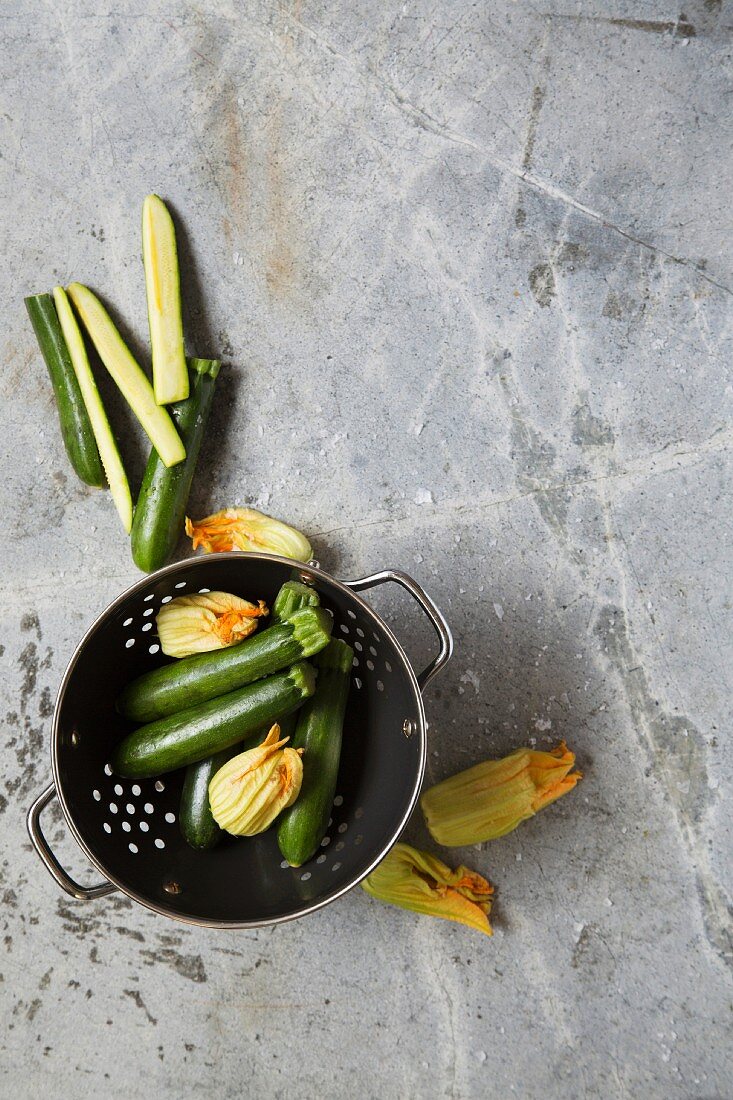 Courgette and courgette flowers in a colander