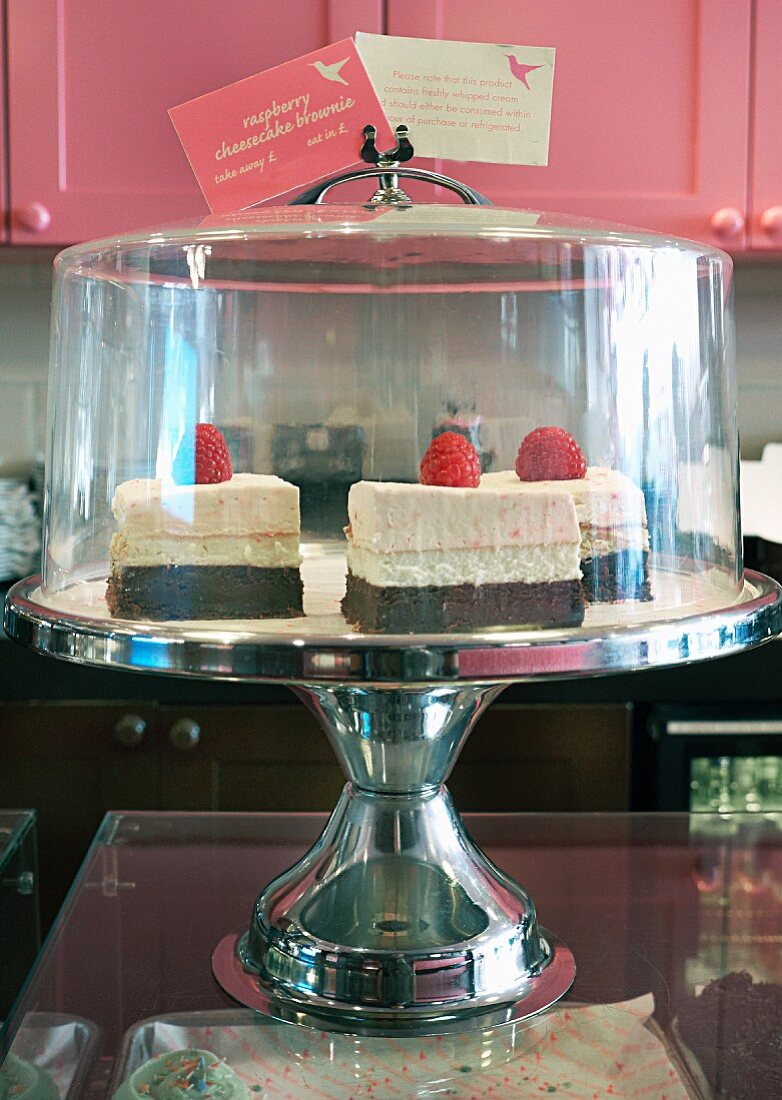 Himbeerkuchen auf Kuchenständer mit Glashaube zur Teatime im Restaurant