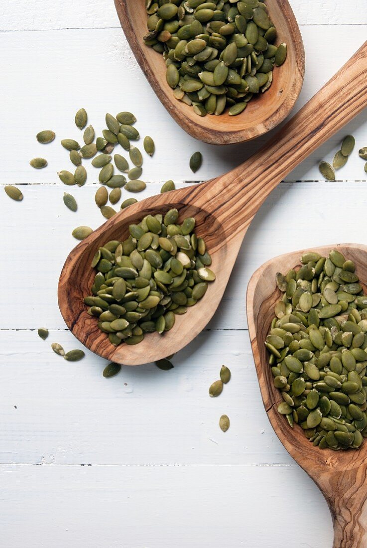 Pumpkin seeds on wooden spoons (seen from above)