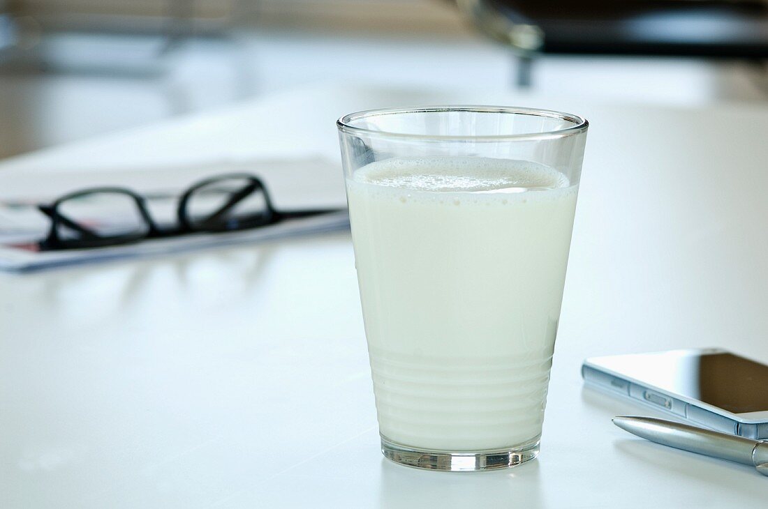A glass of soya milk on a desk in an office