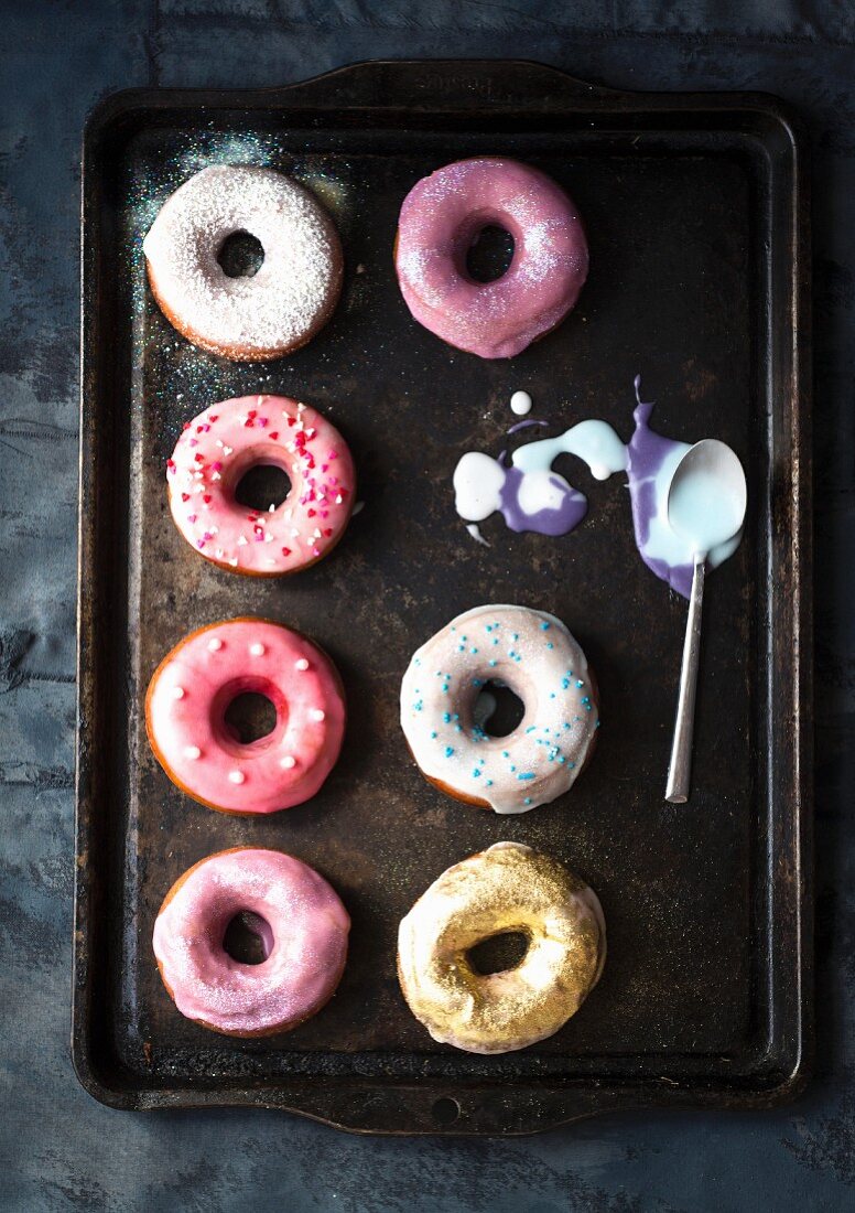 Doughnuts with colourful icing on a baking tray