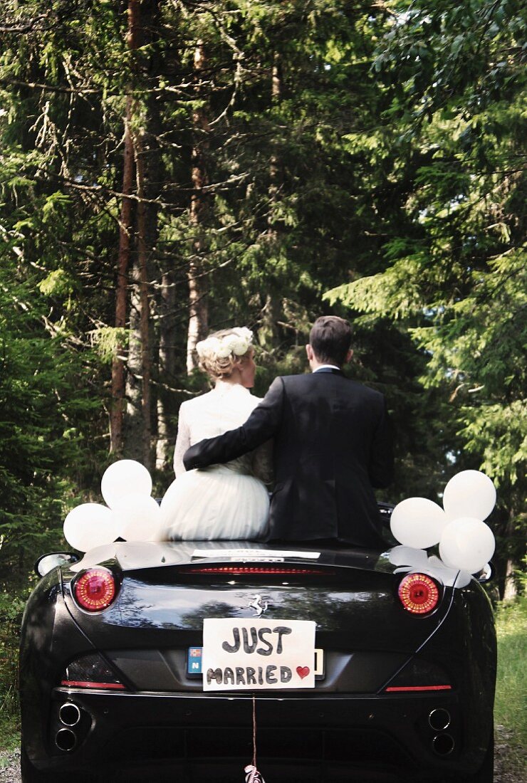 Brautpaar sitzt in Cabrio mit Aufschrift 'Just Married'