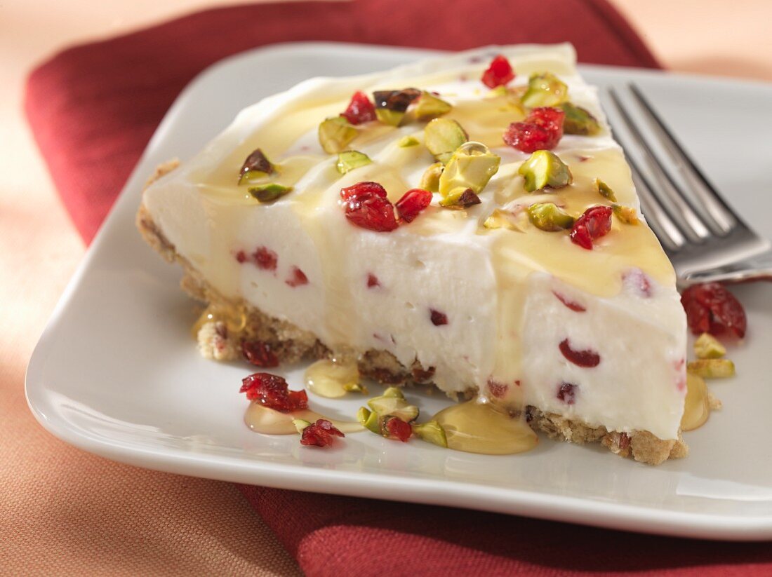 A slice of cranberry pie with pistachio nuts and honey